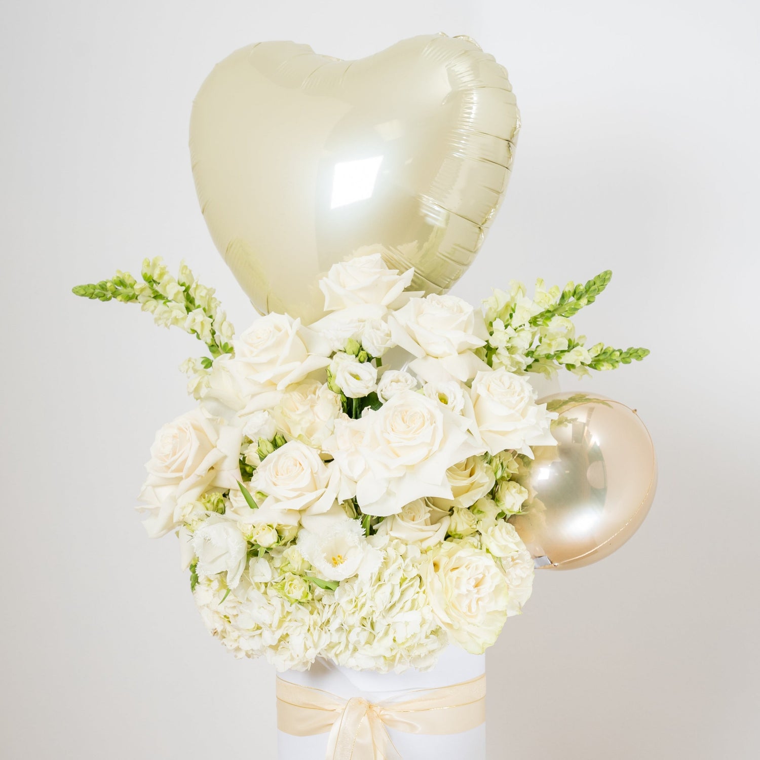 white flower arrangement with a heart balloon on topinside of a white box