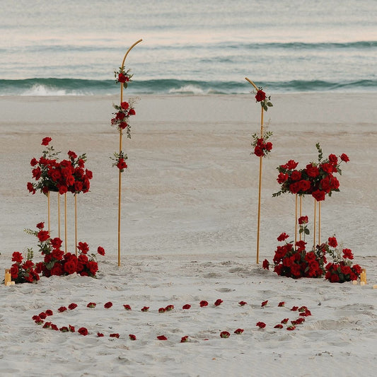 Decorative setup with red flowers on a sandy beach with ocean waves in the background