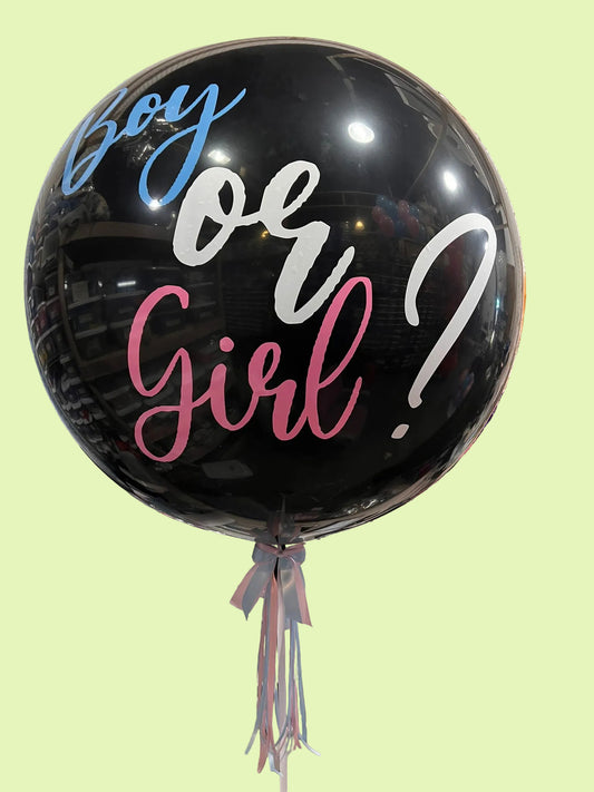 A large black balloon with the words 'Boy or Girl?' in blue, white, and pink script, tied to a table in a party decoration setup.