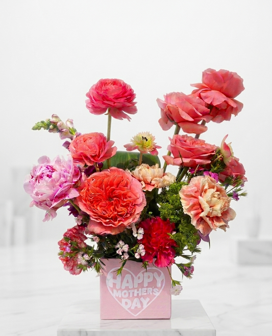 Bouquet of pink and red flowers in a box with 'Happy Mother's Day' text on a white background