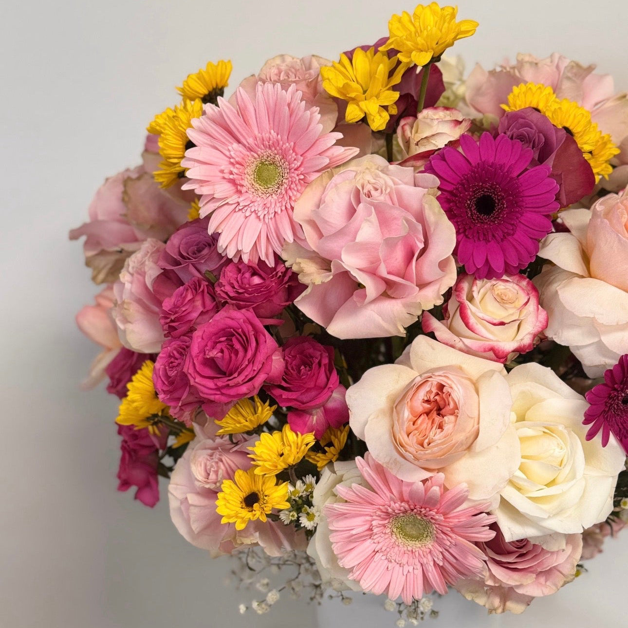Bouquet of colorful flowers in a white vase on a light gray background