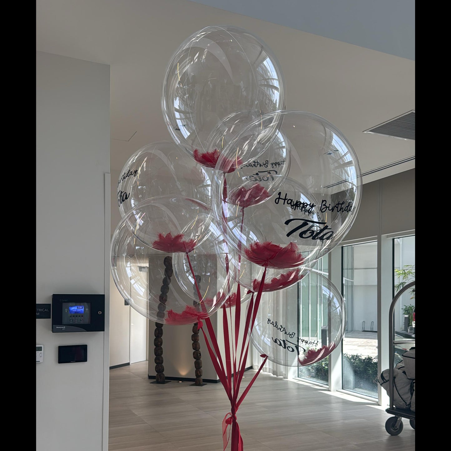 Clear balloons with red ribbons and flowers inside